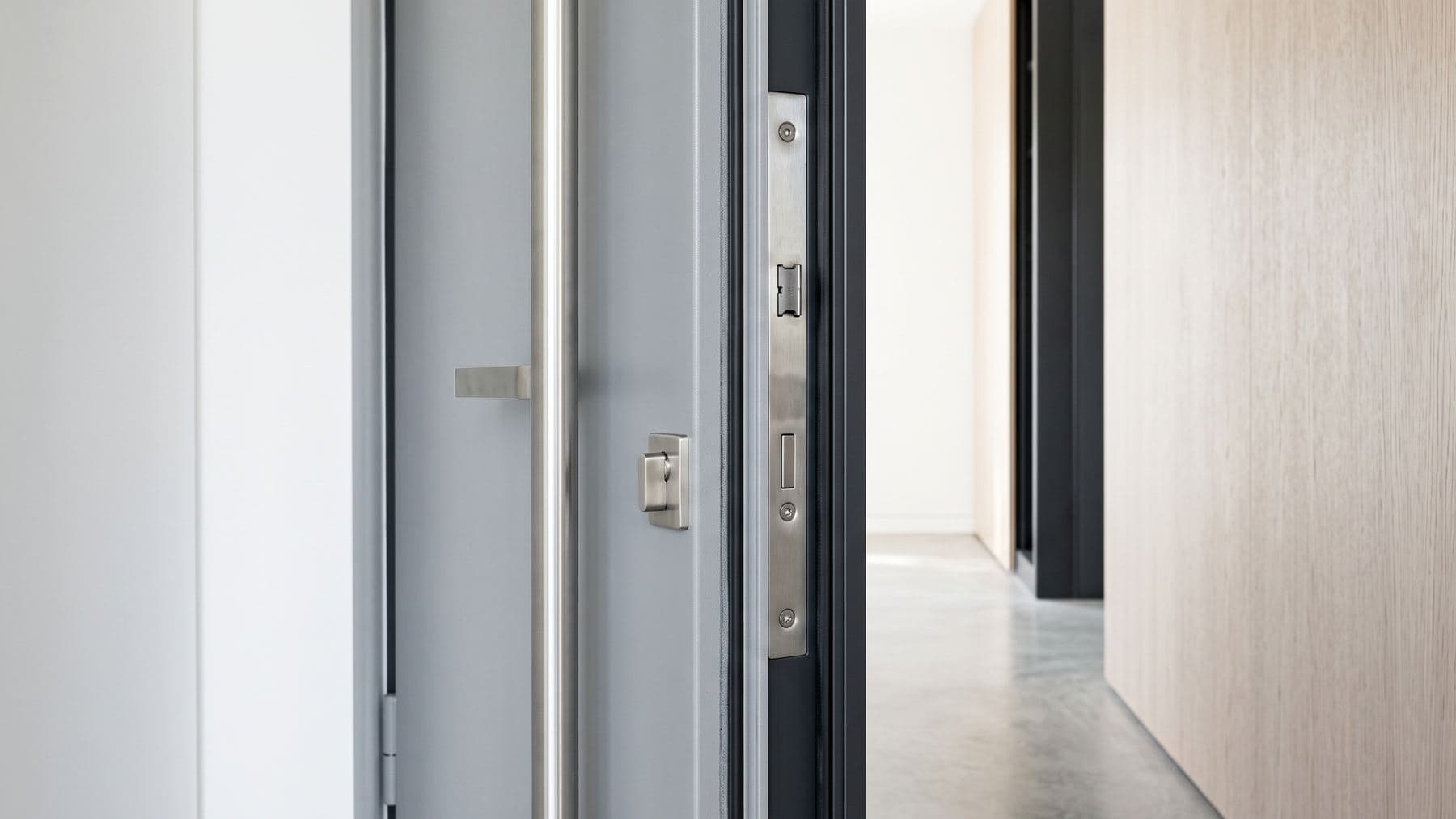 Chant d’un bloc-porte blindé moderne, panneau d’acier gris clair et cornière anti-pince en inox le long du dormant