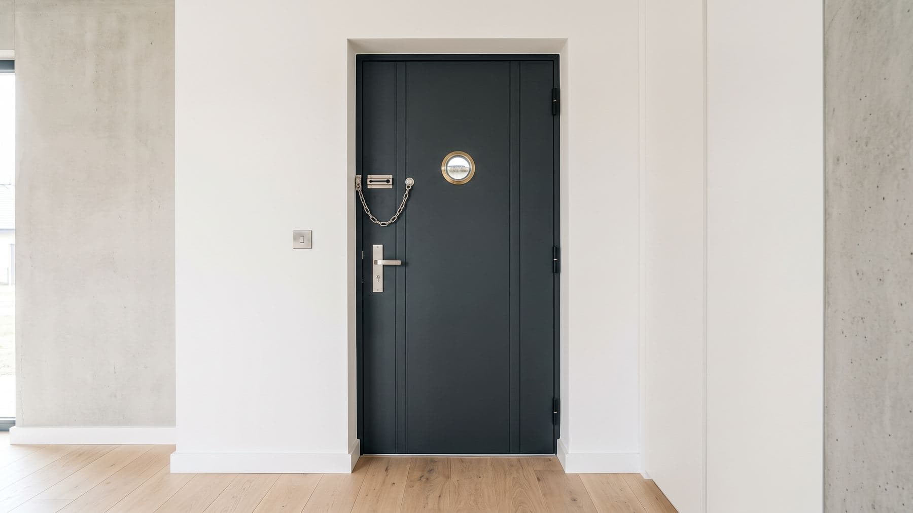 Porte d’entrée contemporaine vue de l’intérieur, entrebâilleur en inox et viseur grand angle neufs